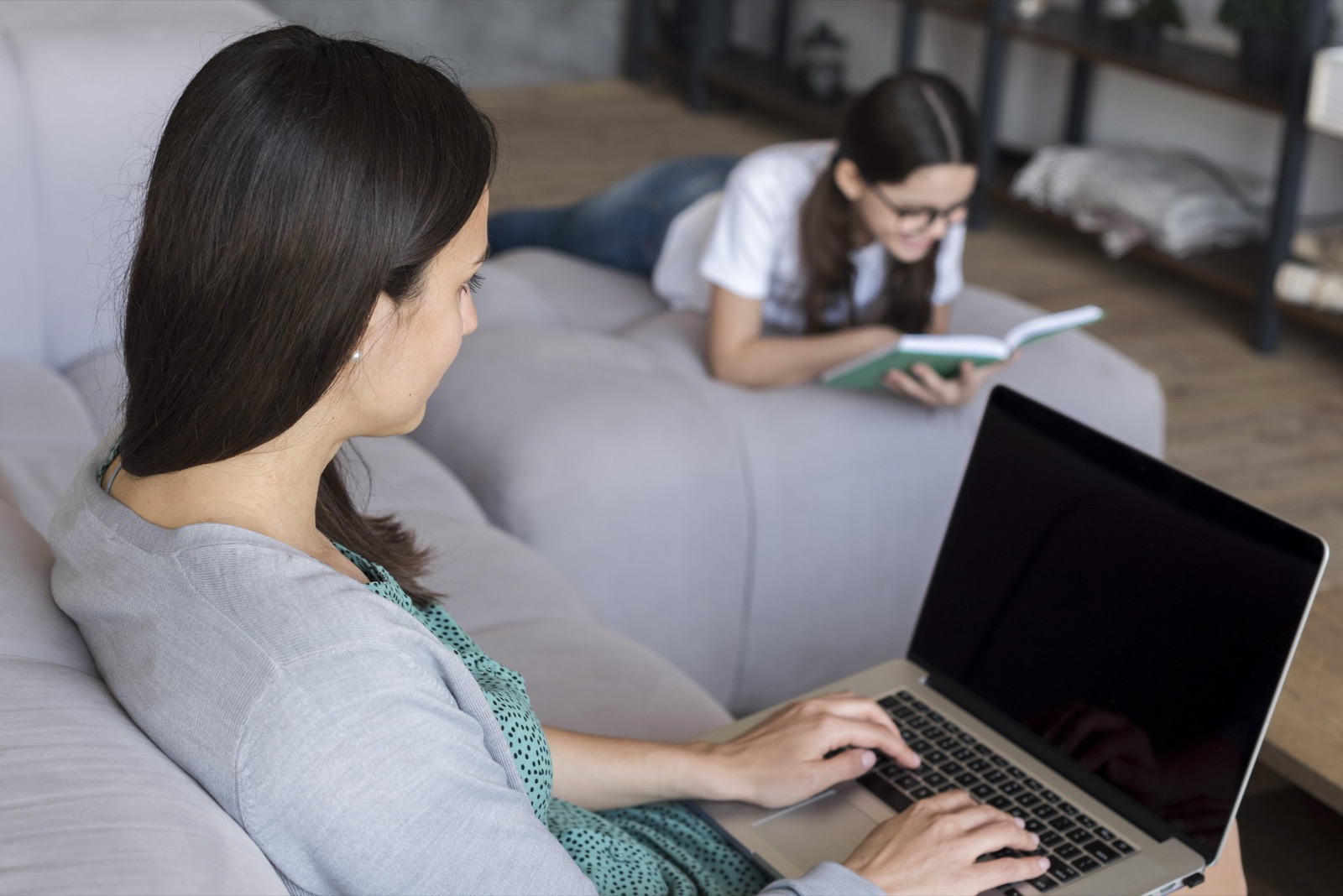 Mujer conectada a internet con su portátil en el sofá de casa
